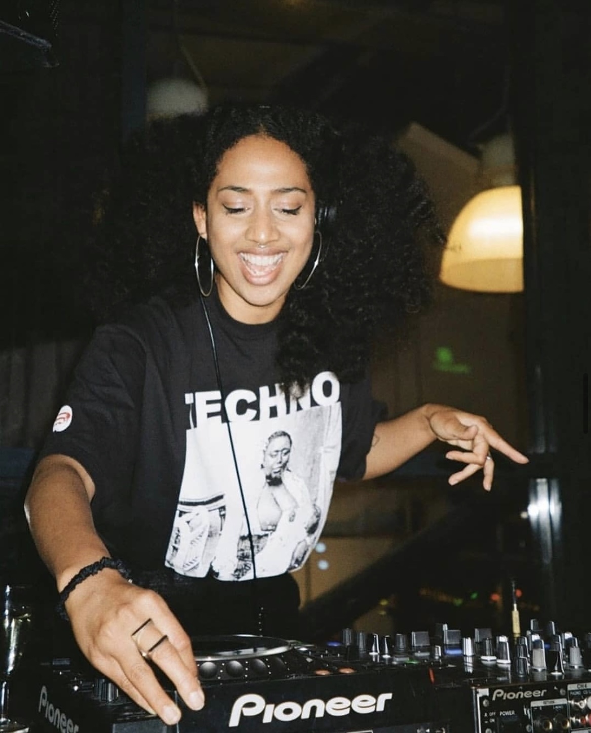 Natalya DJing on Pioneer decks, smiling behind the mixer